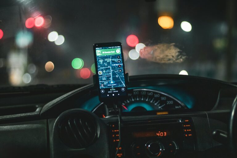 Close-up of a smartphone with map navigation in a car at night with bokeh effect.